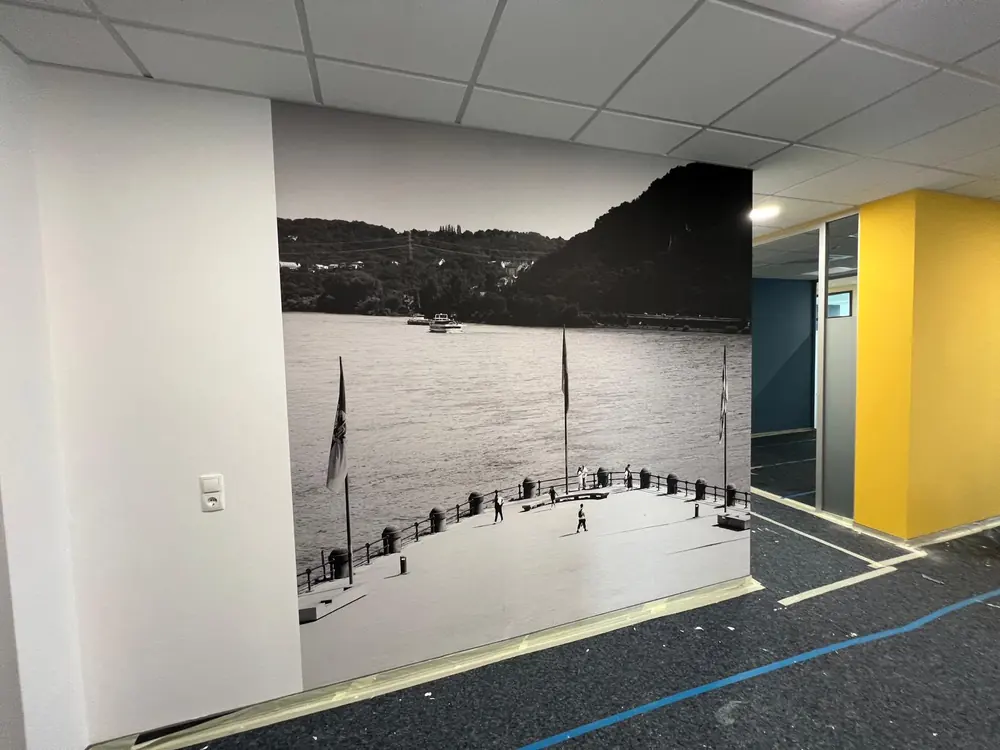 Fototapete mit Seepanorama in einem Büro, daneben eine gelb gestrichene Wand